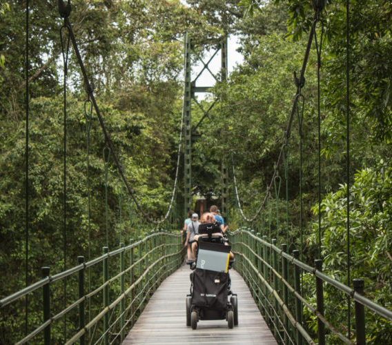 Lady in electric wheelchair crossing a hanging bridge