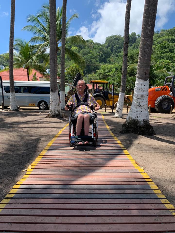 Man in wheelchair on accessible retractable beach walkway