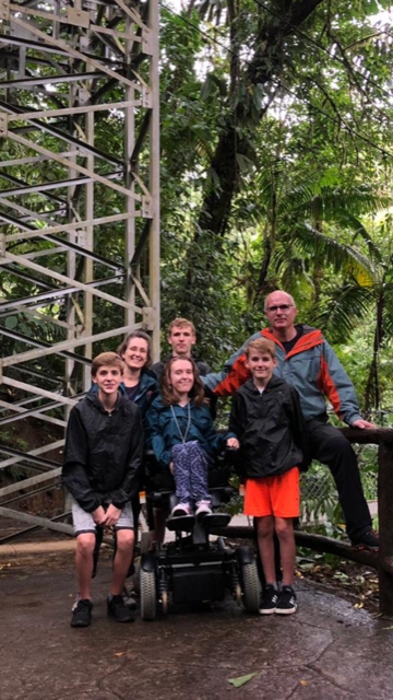 family with girl in a wheel chair outdoors in a rainforest