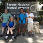 3 men and a lady in wheelchair by the Manuel Antonio National Park sign