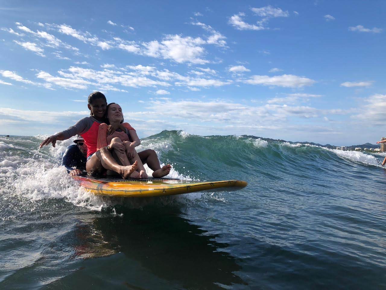 2 women sitted in a surf board