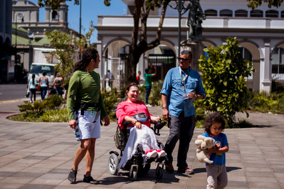 Lady in electric wheelchair with 2 men and a kid rolling around San José downtown